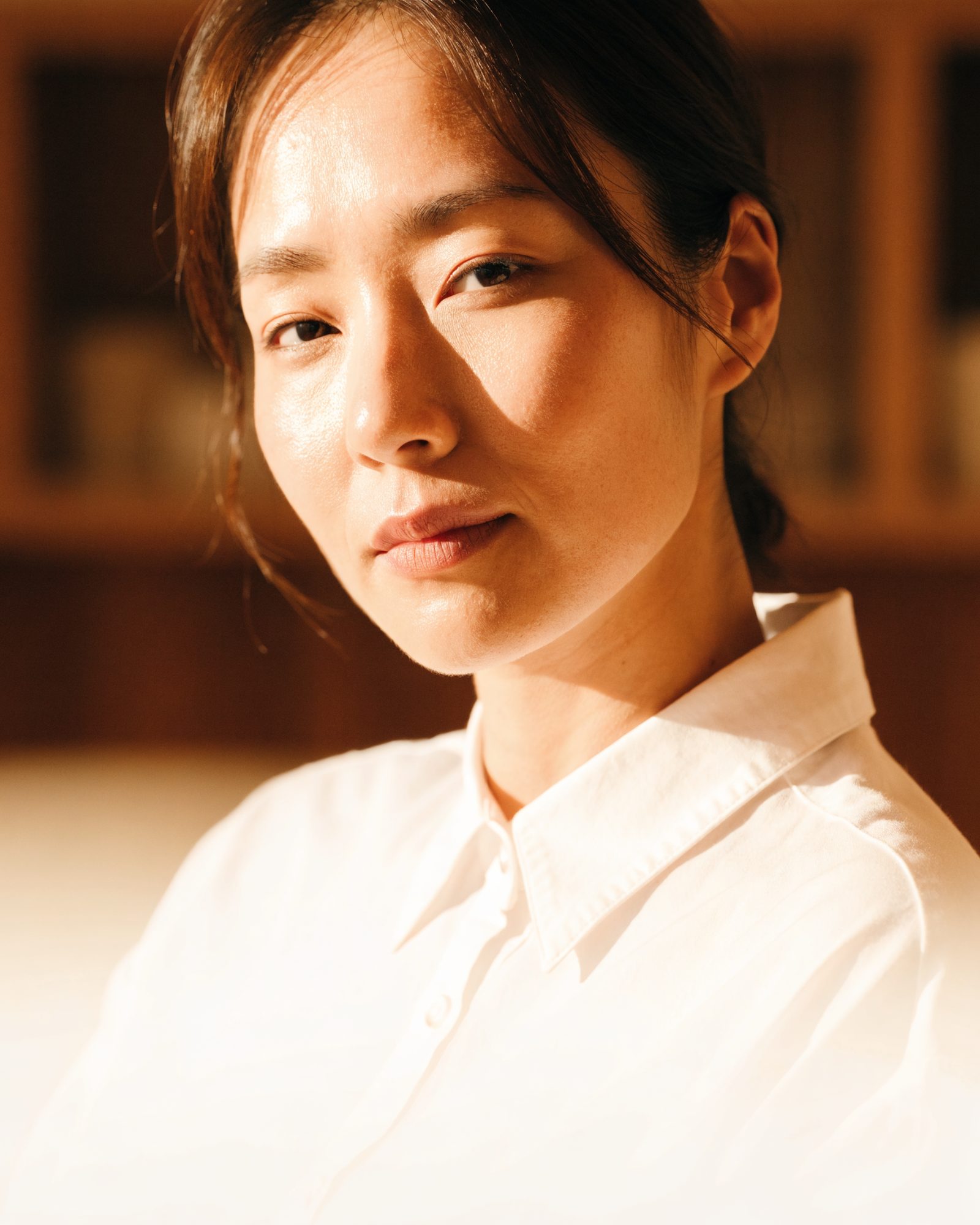 창가 자연광이 드는 트리트먼트룸에서 시술 전 편안한 표정으로 앉아 있는 여성